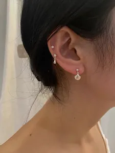 Macro detail of S925 sterling silver shell and mermaid tail stud earrings on model