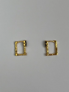 Close-up of golden rectangular earrings featuring black onyx and textured silver finish