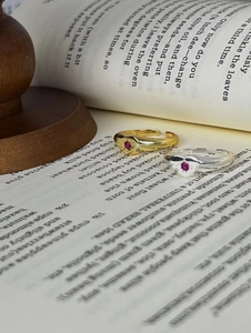 Detail of vintage S925 silver rings with red gemstone and textured band on book page