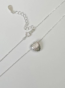 Macro detail of 925 sterling silver heart necklace with ribbed texture and small zircon