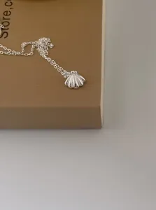 Vue détaillée d'un pendentif coquillage en argent sur une fine chaîne de collier maille