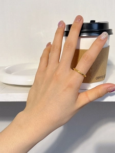 Gros plan d'une bague fine dorée minimaliste portée à l'index dans un décor quotidien