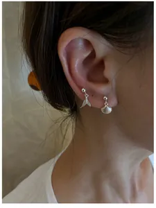 Macro detail of S925 sterling silver mermaid tail and seashell dangle stud earrings