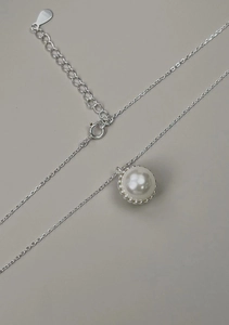 Macro shot of s925 silver necklace featuring a pearl pendant with a serrated metal edge