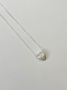 Detailed view of silver heart pendant featuring unique pleated texture and a small crystal