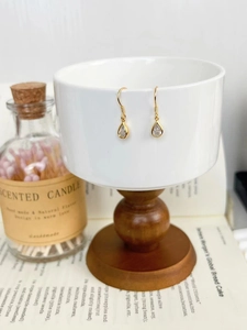Détail de boucles d'oreilles goutte d'argent avec zircone poire sur tasse en céramique