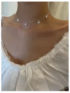 Detail of s925 silver shell choker necklace worn on model for a minimalist layered look