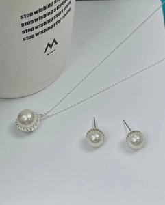 Detail shot of white pearl necklace and stud earrings set with silver scalloped settings
