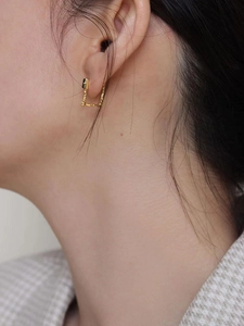Golden textured geometric earrings with zircon detail worn on a female model profile