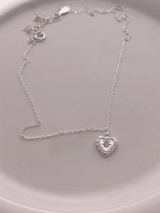 Gros plan d'un pendentif coeur en argent 925 avec diamant étoile et fine chaîne en argent