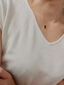 Détail d'un collier vintage en or avec pendentif rectangulaire en onyx noir porté au cou