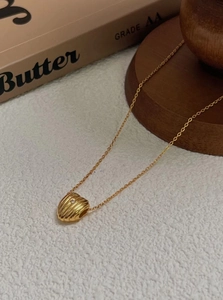 Close-up of golden heart pendant with pleated texture and sparkling center zircon