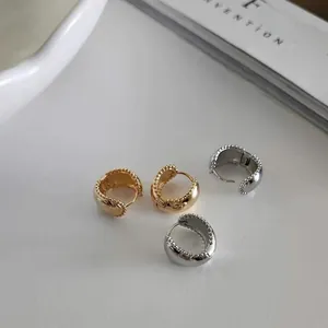 Detail of gold and silver U-shaped earrings with vintage milgrain textured edges