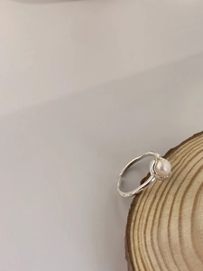 Macro du poinçon argent massif S925 sur bague perle réglable posée sur support bois