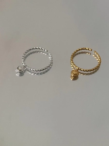 Macro view of silver and gold twist rings featuring 3D heart charms on a mirror surface