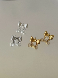 Macro view of metallic bow earrings with vertical stripe texture and polished finish