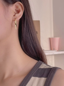 Close-up of golden streamlined twist earrings with minimalist vertical drop on model