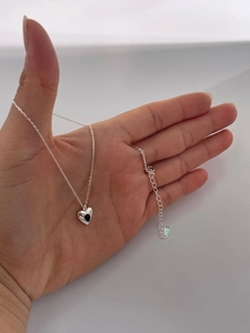 Close-up of S925 silver necklace with black heart pendant held in hand for scale