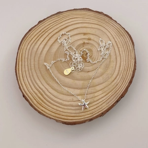 Elegant 925 sterling silver starfish pendant necklace on natural wood background
