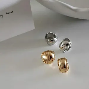 Minimalist gold and silver hoop earrings with milgrain edge on a white ceramic plate