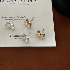 Detail of 925 sterling silver pearl stud earrings in gold and silver set on a display card