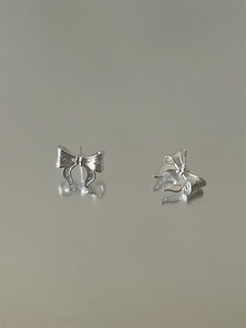 Close-up of silver bow stud earrings with textured finish and reflective mirror surface