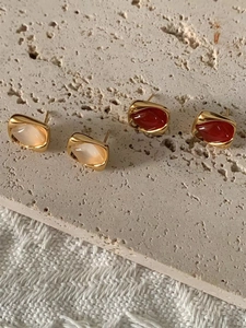 Vue détaillée de boucles d'oreilles géométriques irrégulières en crème et rouge foncé