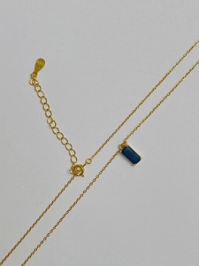 Gros plan du poinçon S925 sur la chaîne dorée avec pendentif en pierre bleue