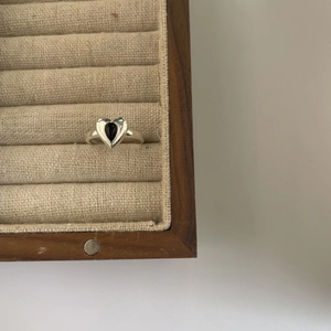 925 silver open ring featuring a black heart-shaped gemstone on a wooden jewelry display