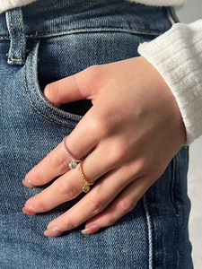 Close-up of gold and silver rope twist rings with heart charms on a model finger