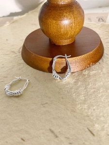 Vue macro de boucles d'oreilles créoles ovales en argent S925 avec texture torsadée
