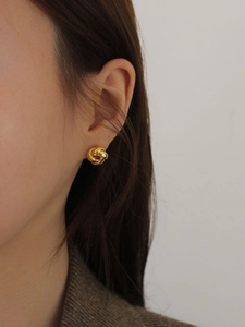 Close-up of a 925 sterling silver knot stud earring in gold worn by a model