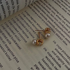 Elegant gold pearl and zircon stud earrings on vintage book page for women