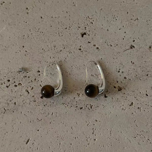 Elegant silver tiger eye drop earrings with a minimalist sleek design on stone texture