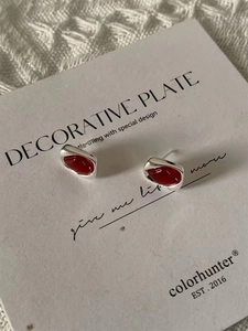 Gros plan de boucles d'oreilles géométriques en argent avec pierres rouges en goutte