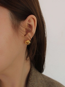 Minimalist 925 sterling silver golden knot stud earrings worn by a model in warm tones