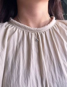 Close-up of minimalist sterling silver heart pendant necklace worn on a female neck