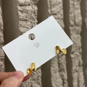 Detailed view of gold S925 sterling silver twisted wave earrings on display card