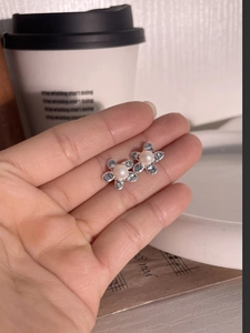 Elegant 925 silver flower stud earrings with pearl center shown on a fingertip