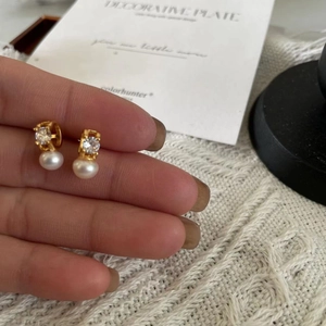 Detailed shot of pearl drop earrings with zircon studs and gold finish base