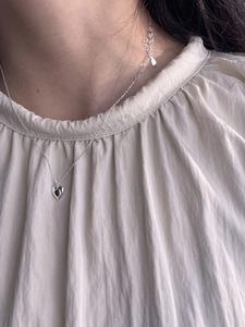 Close-up of 925 sterling silver necklace with black heart pendant on female neck
