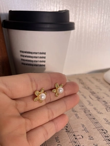 Macro detail of a 925 silver pearl flower earring with hammered gold finish texture