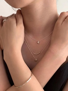 Detail of layered gold necklaces with starfish and shell pendants on female model