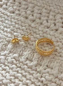 Macro detail of gold double-layer open ring and bean earrings on white knit fabric