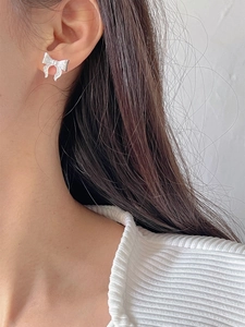 Close-up of elegant silver bow earrings with textured finish worn by a model