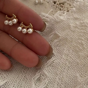 Detailed close-up of 925 silver pearl stud earrings with a curved gold diamond setting