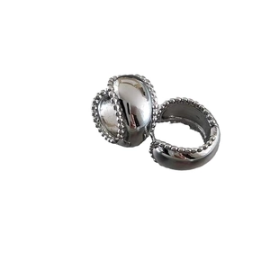 Polished silver chunky hoop earrings with textured bead edges on white background