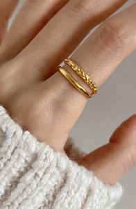 Detail of stacked gold layering rings featuring a smooth band and hammered texture finish