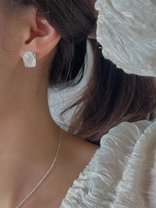 Détail d'une boucle d'oreille carrée en argent avec incrustation de nacre sur mannequin