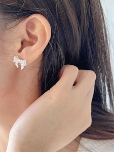 Elegant silver bow earrings with textured finish shown on model for a chic look
